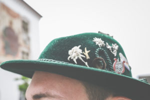 The head of a man with a Bavarian traditional hat and individual badges and lucky charms on it. The head of a man with a Bavarian traditional hat and individual badges and lucky charms on it.